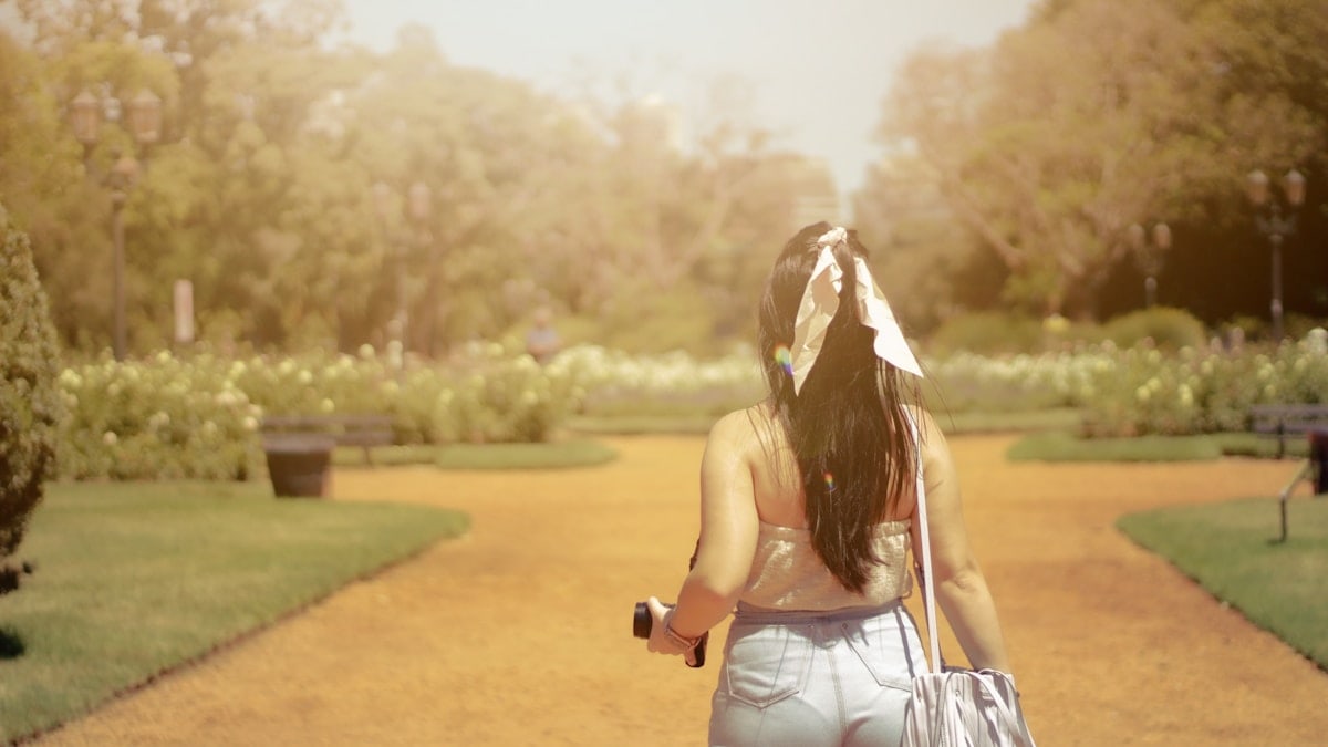 girl walking in a park holding a camera